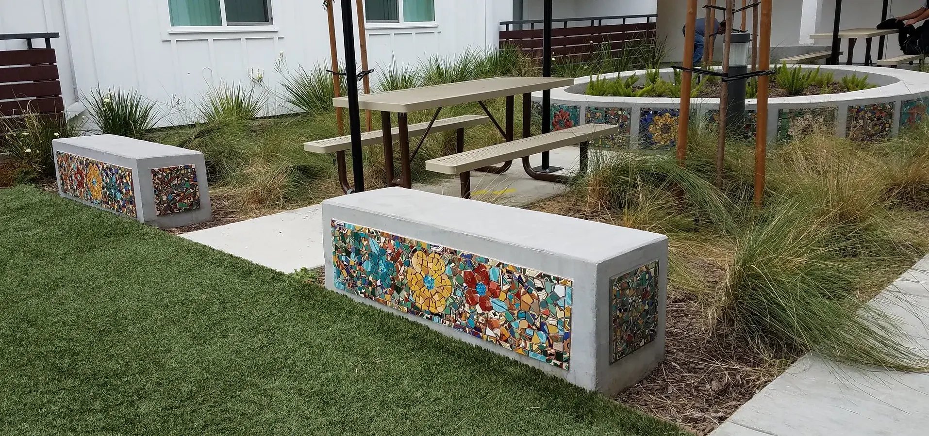 Completed mosaic pieces on community benches in a community space.