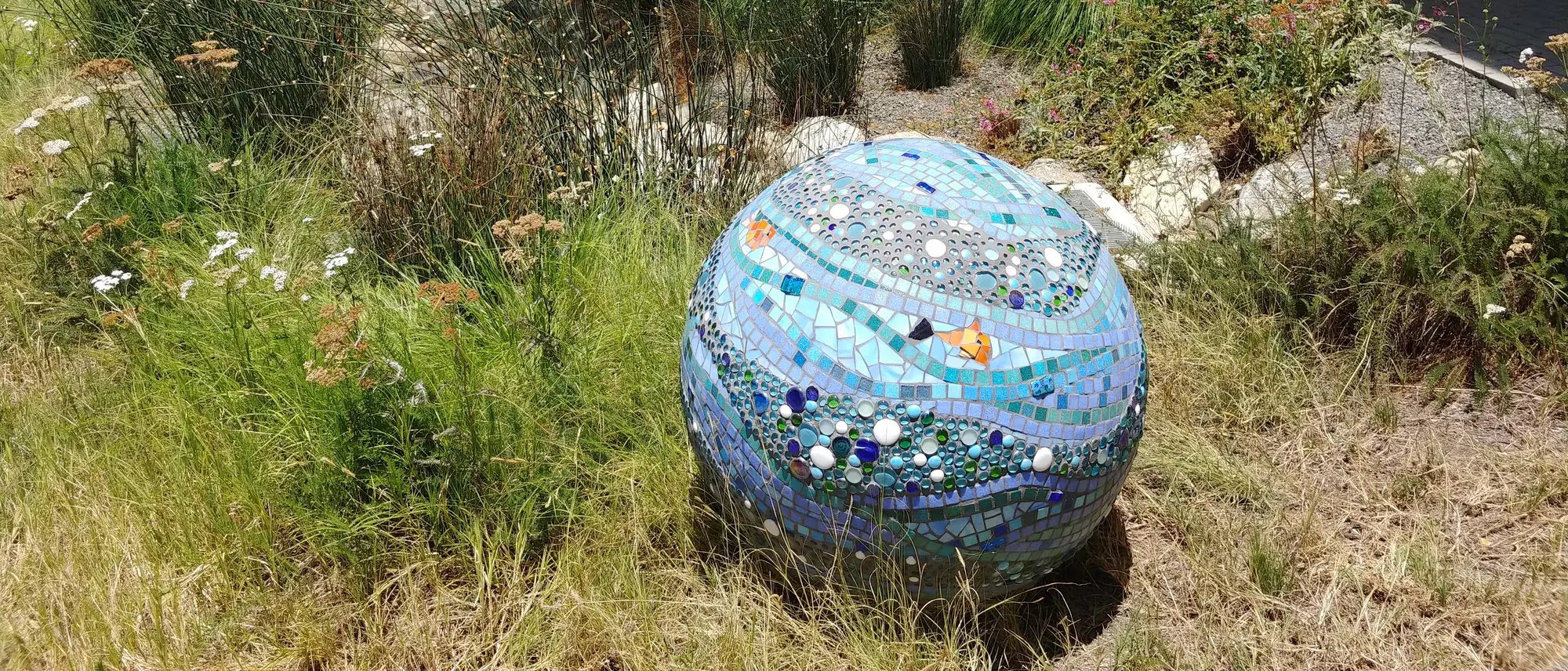 Completed garden sphere mosaic with shades of blue and mosaics of fish.