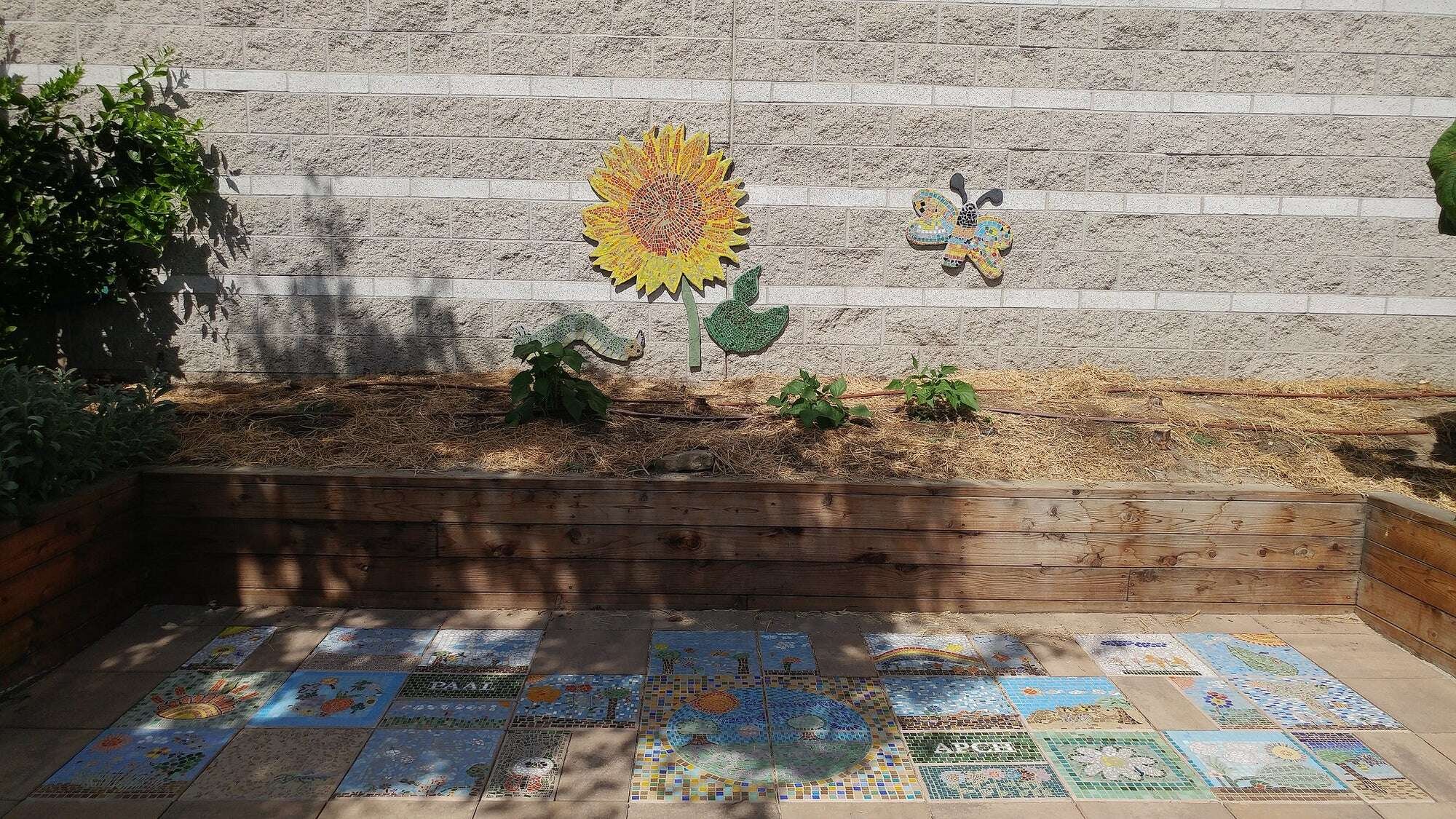 The completed mosaic sunflower, butterfly, and tiles in the central ave garden.