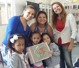Kids from the community posing with a mosaic flower they created during a workshop.